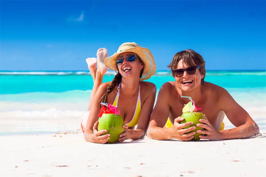 Frisch verheiratetes Ehepaar genießt fruchtige Drinks am Strand