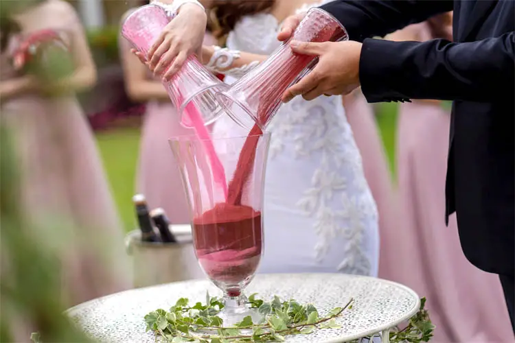 Hochzeitspaar schüttet bunten Sand in Vase