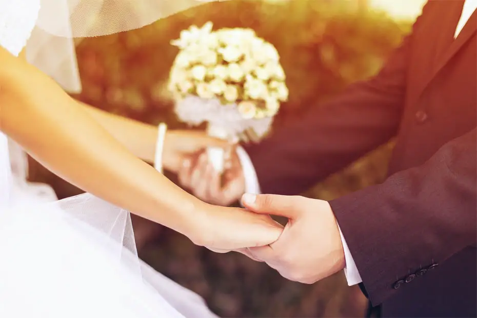 Das frisch verheiratete Ehepaar hält sich glücklich an den Händen