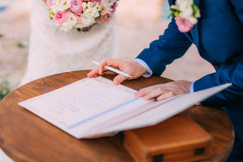 Hochzeitspaar leistet beim Standesamt die Unterschrift