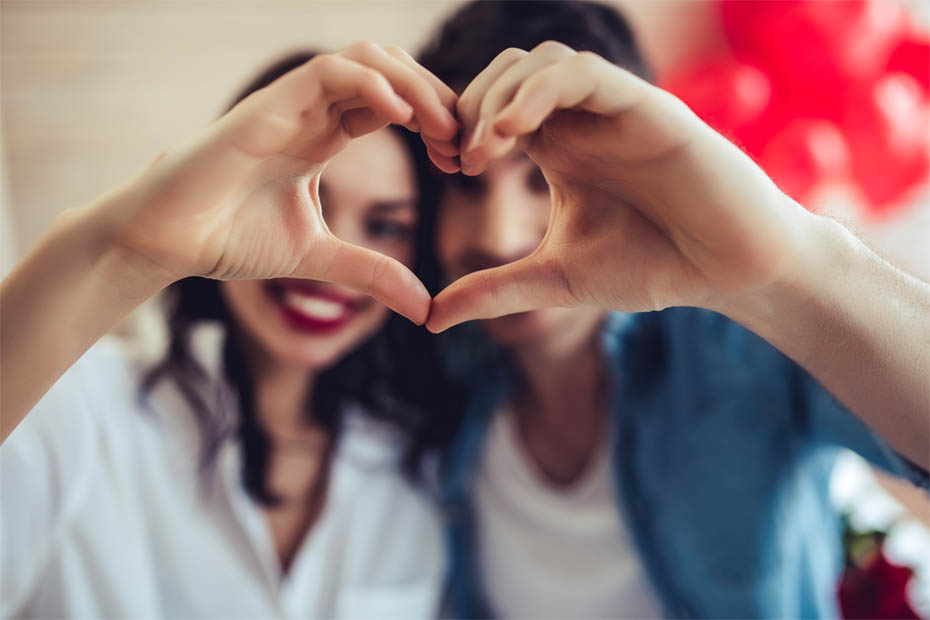 Paar formt zum Valentinstag ein Herz mit den Händen